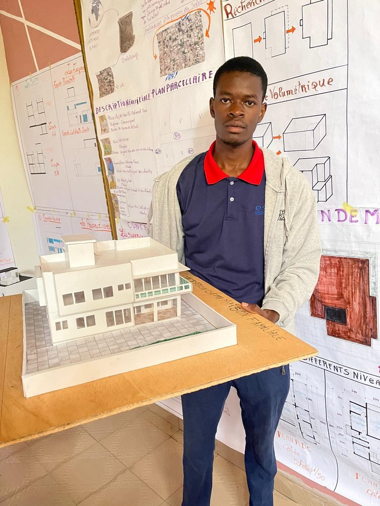 Un étudiant présente une maquette blanche devant ses plans