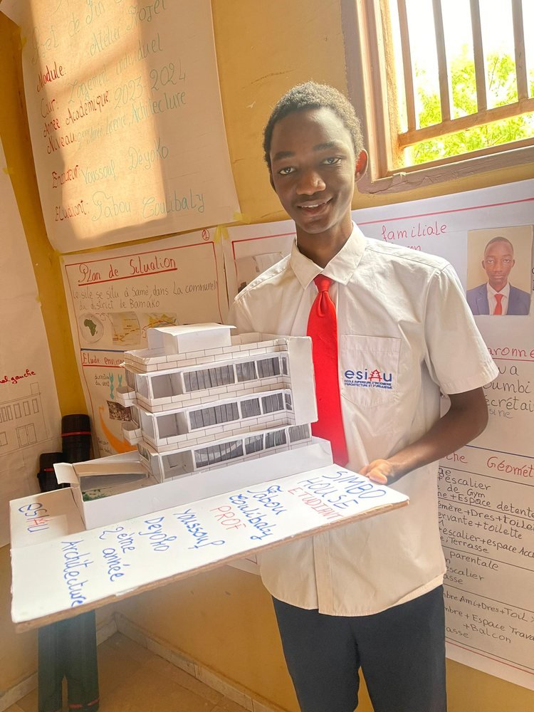Un étudiant sourit devant sa maquette
