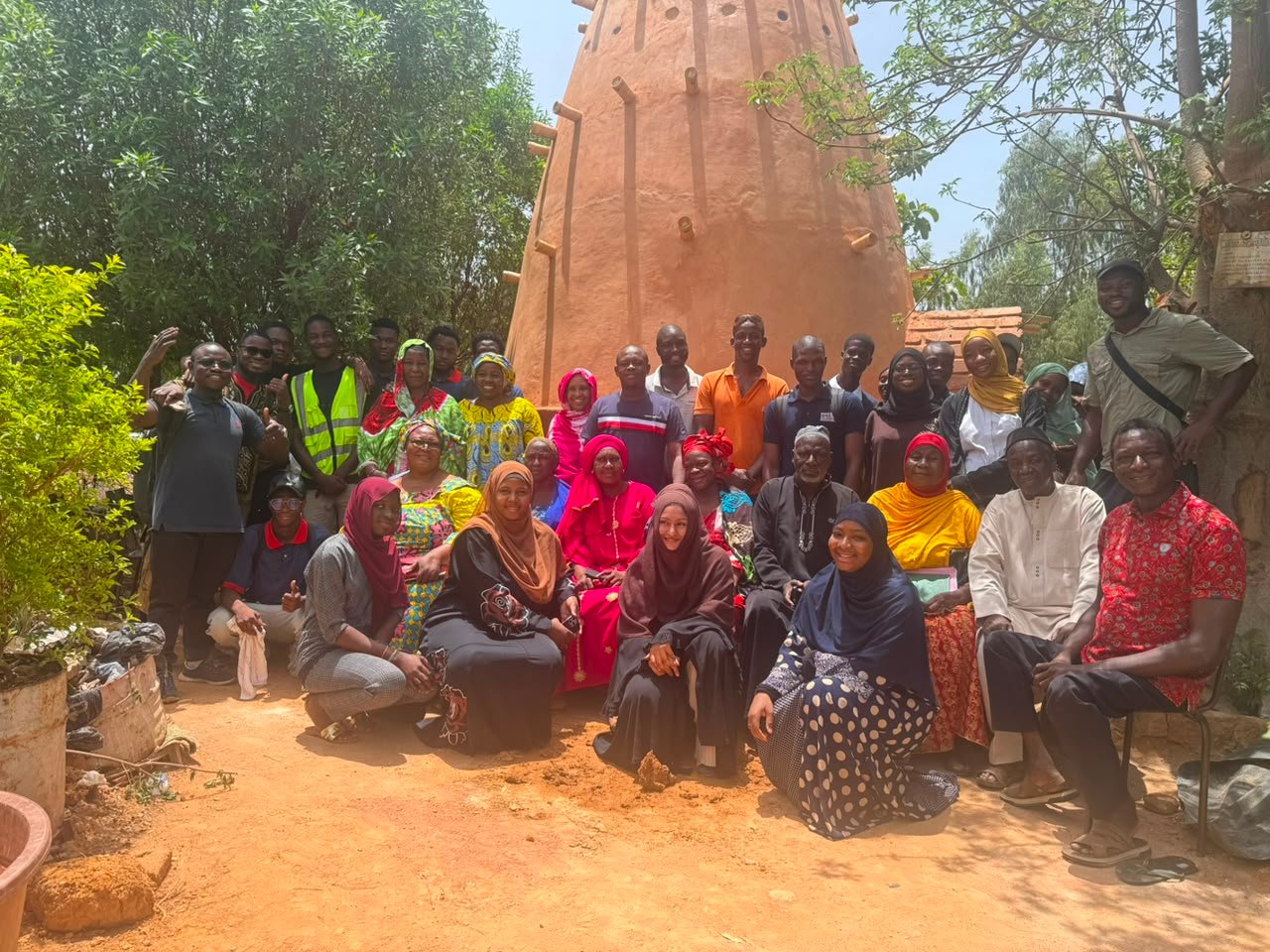 Étudiants et habitants devant une tour en terre crue construite lors d'un atelier